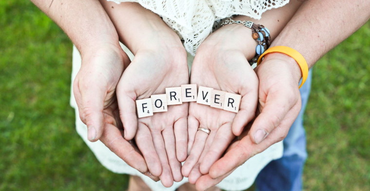Man holding womans hands holding letters spelling out forever